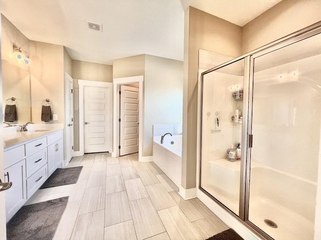 bathroom with vanity and shower with separate bathtub