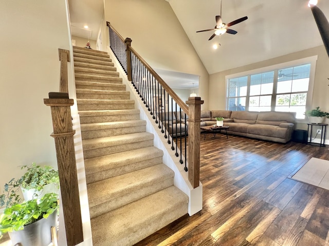 stairway featuring ceiling fan, hardwood / wood-style floors, and high vaulted ceiling