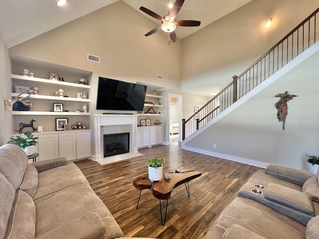 living room featuring ceiling fan, dark hardwood / wood-style flooring, high vaulted ceiling, and built in shelves