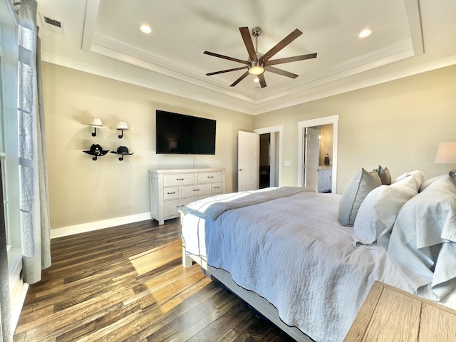 bedroom featuring ceiling fan, dark hardwood / wood-style flooring, a tray ceiling, and connected bathroom