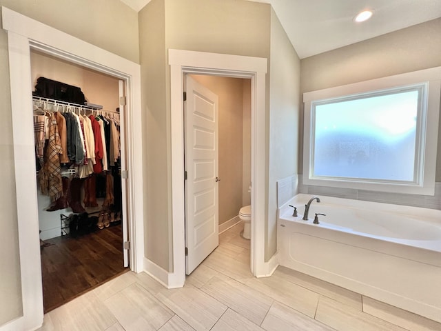 bathroom with toilet and a tub to relax in