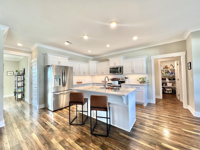 kitchen with white cabinetry, dark hardwood / wood-style flooring, stainless steel appliances, backsplash, and a center island with sink