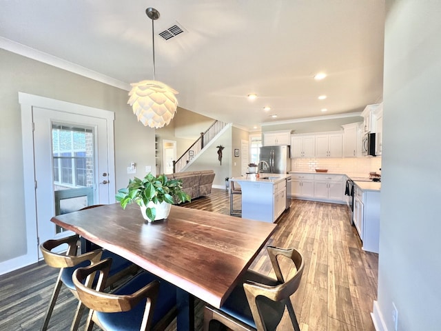 dining room with sink, crown molding, and hardwood / wood-style floors