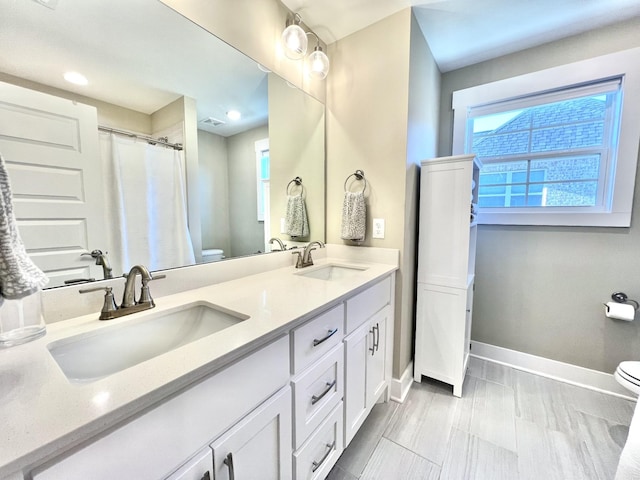 bathroom featuring plenty of natural light, toilet, and vanity