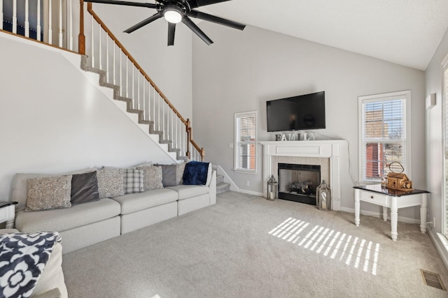 carpeted living room with ceiling fan, a fireplace, and high vaulted ceiling