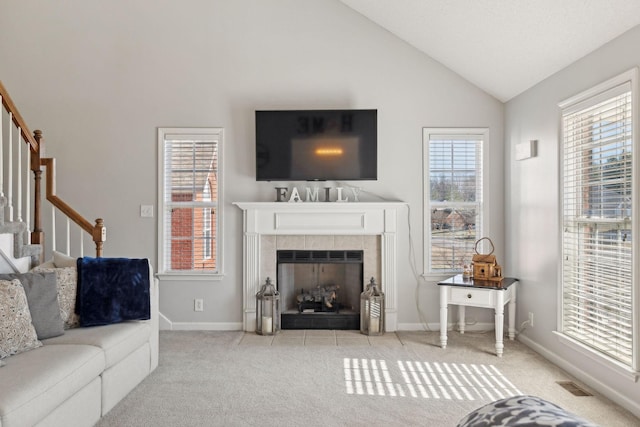 carpeted living room featuring a tiled fireplace and vaulted ceiling