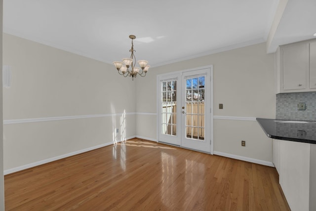 unfurnished dining area with french doors, sink, light hardwood / wood-style flooring, and a notable chandelier