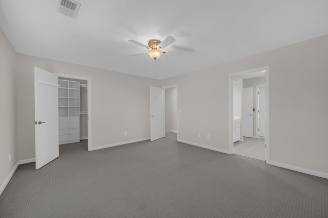 unfurnished bedroom with ceiling fan, light colored carpet, ensuite bathroom, and a closet