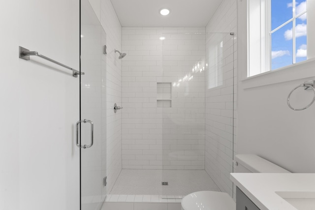 bathroom with a shower with shower door, vanity, and toilet