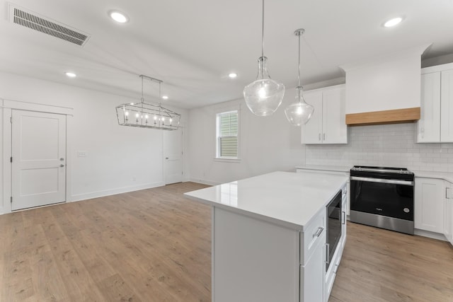 kitchen with appliances with stainless steel finishes, decorative backsplash, white cabinetry, and a kitchen island