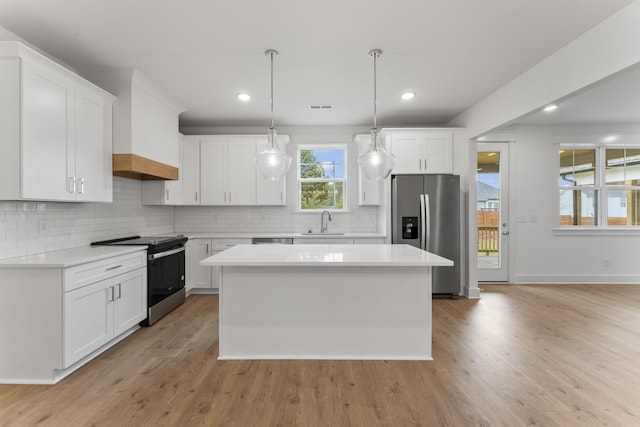 kitchen with pendant lighting, white cabinets, a center island, stainless steel appliances, and sink