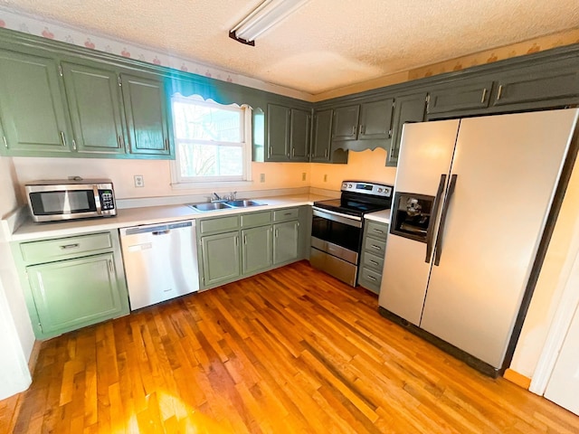 kitchen featuring sink, a textured ceiling, appliances with stainless steel finishes, and light hardwood / wood-style flooring