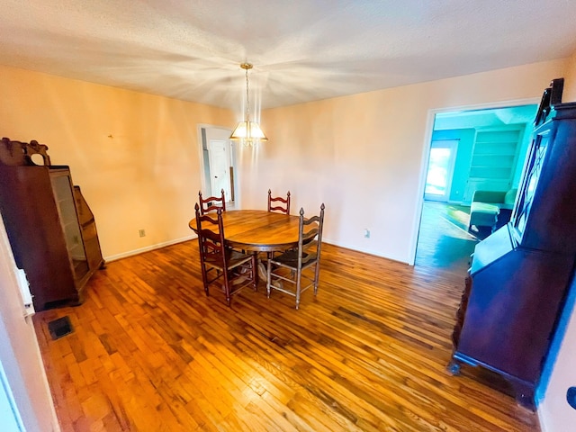 dining room featuring a textured ceiling, dark hardwood / wood-style floors, and a notable chandelier