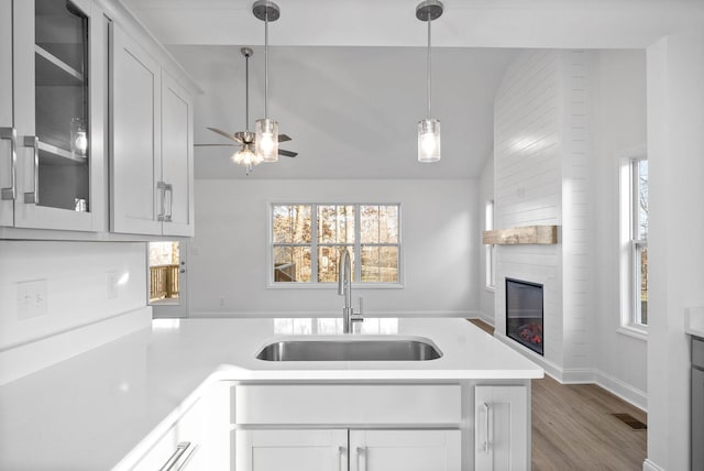 kitchen featuring a large fireplace, sink, white cabinetry, and plenty of natural light