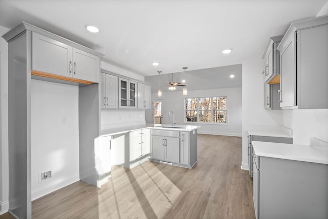 kitchen featuring kitchen peninsula, ceiling fan, gray cabinetry, decorative light fixtures, and sink