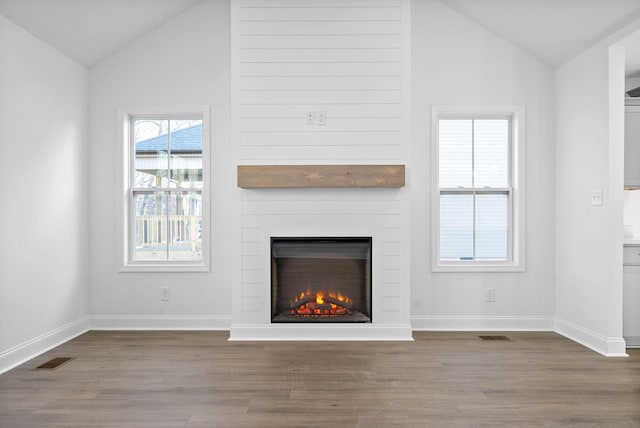 unfurnished living room with vaulted ceiling, a fireplace, and hardwood / wood-style floors