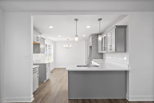 kitchen with gray cabinets, pendant lighting, kitchen peninsula, and sink