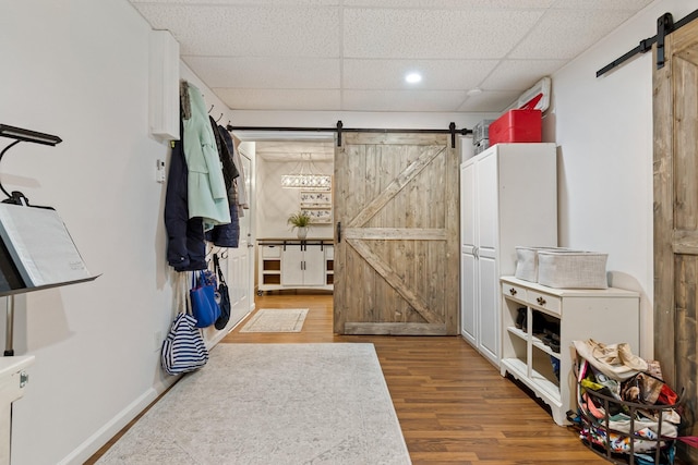 mudroom featuring wood-type flooring, a paneled ceiling, and a barn door