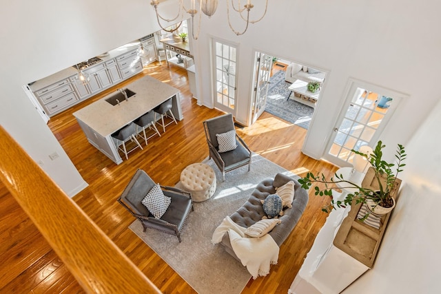 living room featuring sink, hardwood / wood-style floors, an inviting chandelier, and a high ceiling