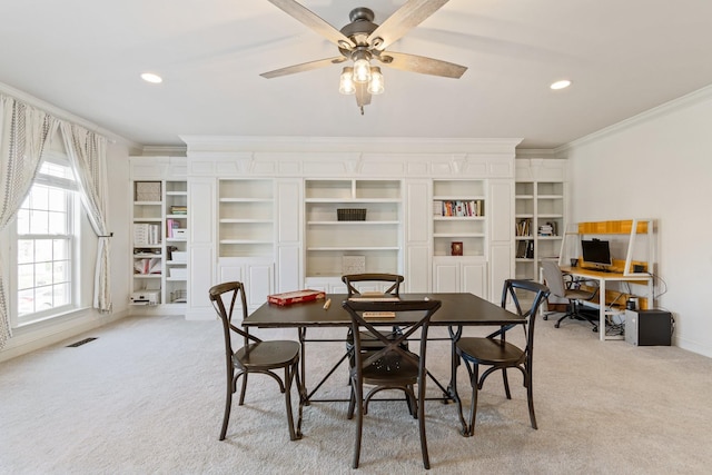 dining room featuring crown molding, light colored carpet, and ceiling fan