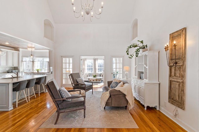 living room featuring light hardwood / wood-style floors, high vaulted ceiling, and an inviting chandelier