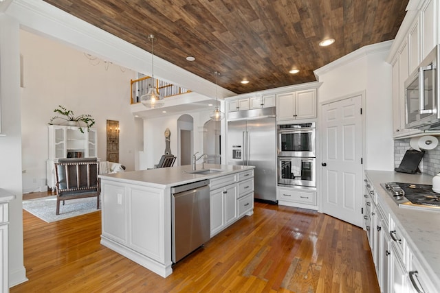 kitchen featuring decorative light fixtures, an island with sink, white cabinetry, and appliances with stainless steel finishes