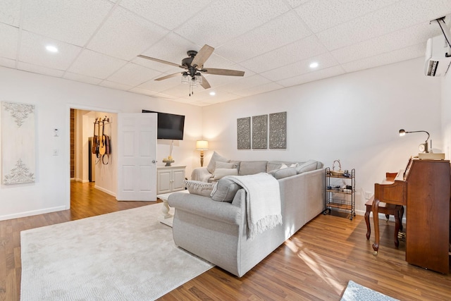 living room featuring wood-type flooring, a paneled ceiling, and ceiling fan