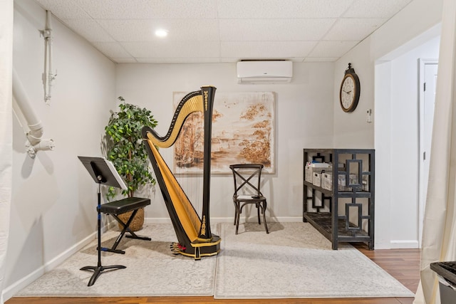 interior space featuring hardwood / wood-style flooring, a paneled ceiling, and a wall mounted air conditioner