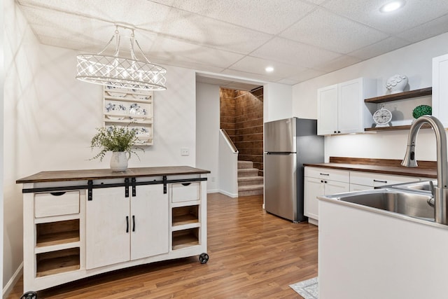 kitchen with white cabinets, butcher block counters, pendant lighting, and stainless steel fridge