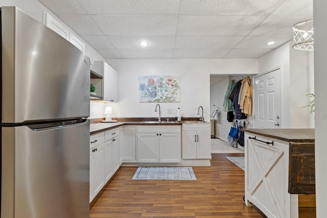 kitchen with wood counters, decorative light fixtures, white cabinetry, sink, and stainless steel fridge