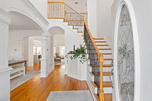 entrance foyer with crown molding, ornate columns, and light wood-type flooring