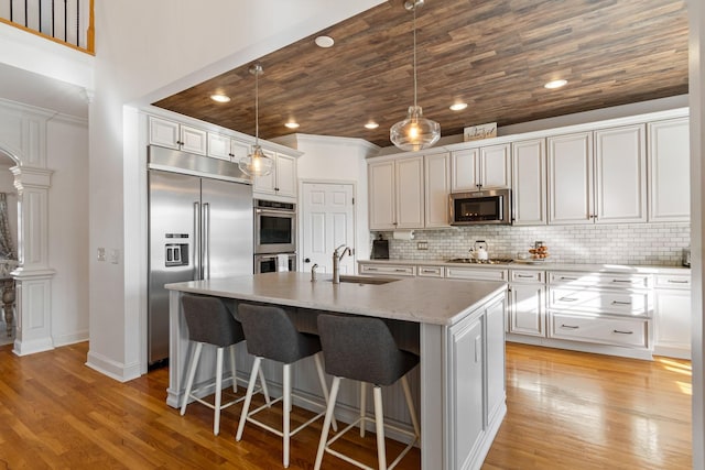 kitchen with light stone countertops, white cabinets, stainless steel appliances, an island with sink, and sink