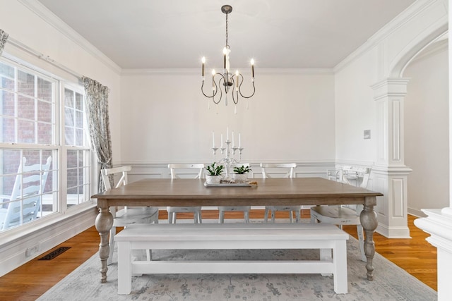 dining room featuring light wood-type flooring, ornate columns, and ornamental molding