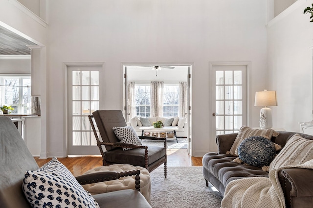 living room featuring ceiling fan, a towering ceiling, and light wood-type flooring