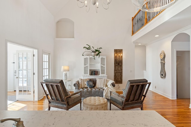 living room featuring a towering ceiling, light hardwood / wood-style flooring, and crown molding