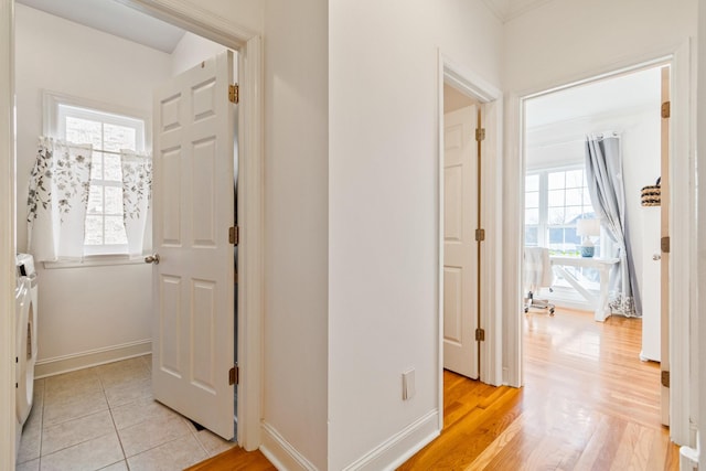 corridor featuring a wealth of natural light, washer and clothes dryer, and light wood-type flooring