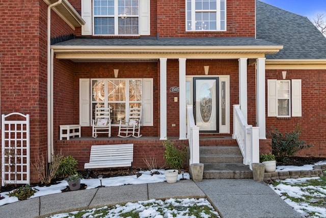 snow covered property entrance with a porch