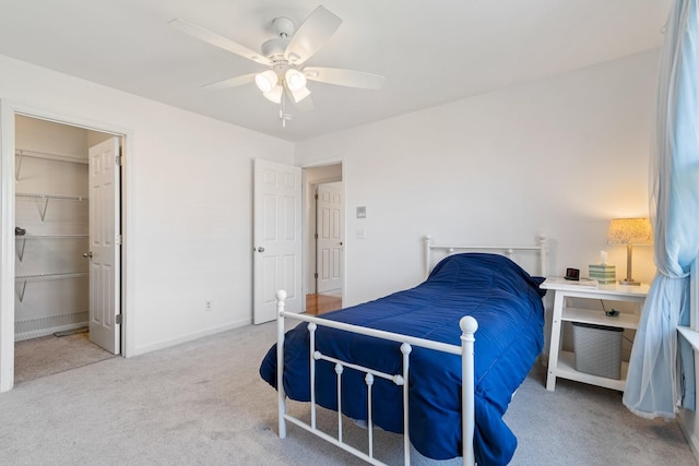 bedroom featuring ceiling fan, a walk in closet, a closet, and carpet floors