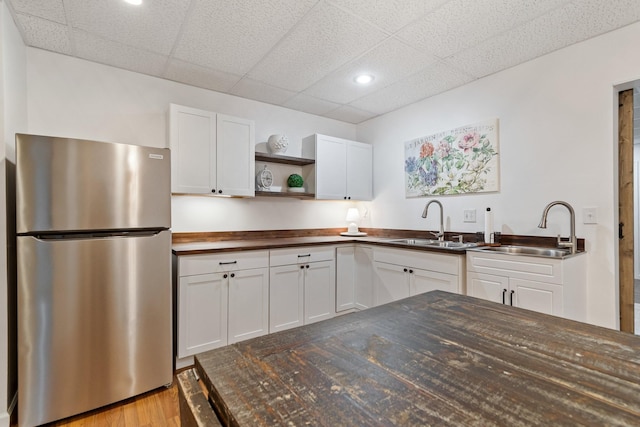 kitchen featuring sink, butcher block countertops, white cabinets, and stainless steel refrigerator