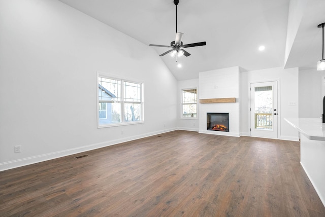 unfurnished living room with dark wood-type flooring, ceiling fan, a fireplace, and high vaulted ceiling