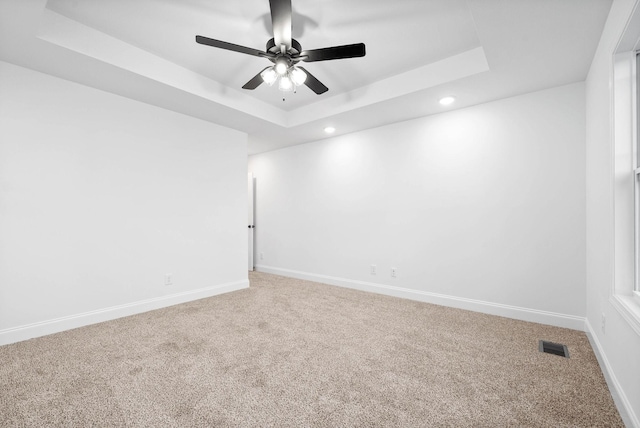 carpeted spare room featuring ceiling fan and a tray ceiling