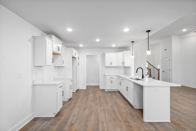 kitchen with pendant lighting, dark wood-type flooring, white cabinetry, sink, and kitchen peninsula