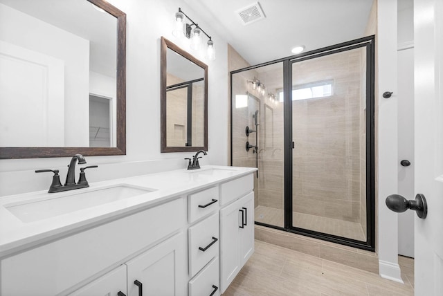 bathroom featuring a shower with door and vanity