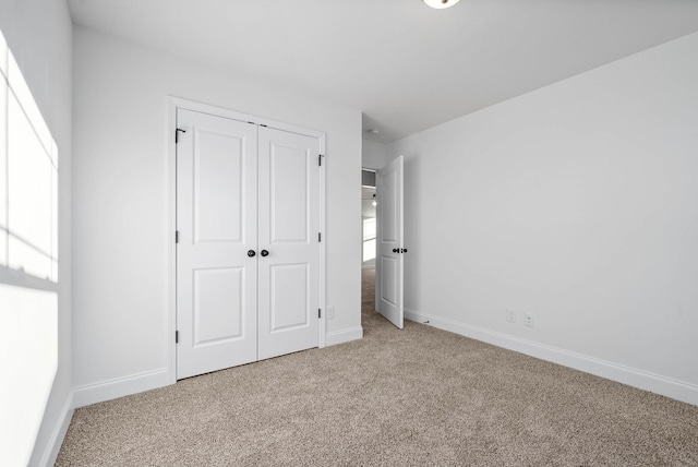 unfurnished bedroom featuring a closet and light colored carpet