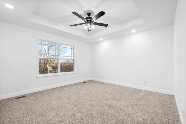 unfurnished room with ceiling fan, a tray ceiling, and carpet flooring