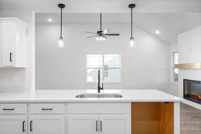 kitchen with ceiling fan, vaulted ceiling, kitchen peninsula, sink, and white cabinets