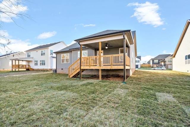 rear view of property featuring ceiling fan, a wooden deck, and a lawn