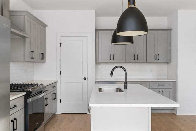 kitchen with gray cabinets, pendant lighting, decorative backsplash, sink, and gas range