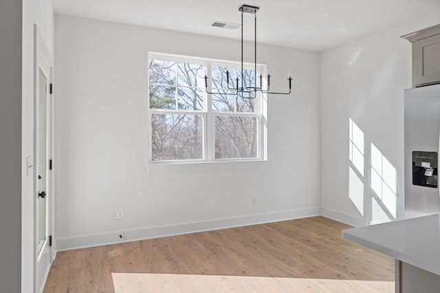 unfurnished dining area with an inviting chandelier and light hardwood / wood-style floors