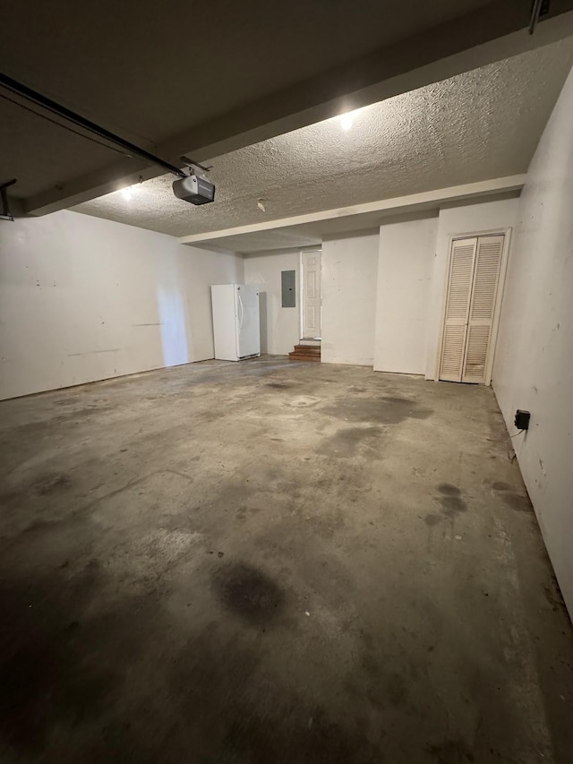 garage featuring a garage door opener, white refrigerator, and electric panel